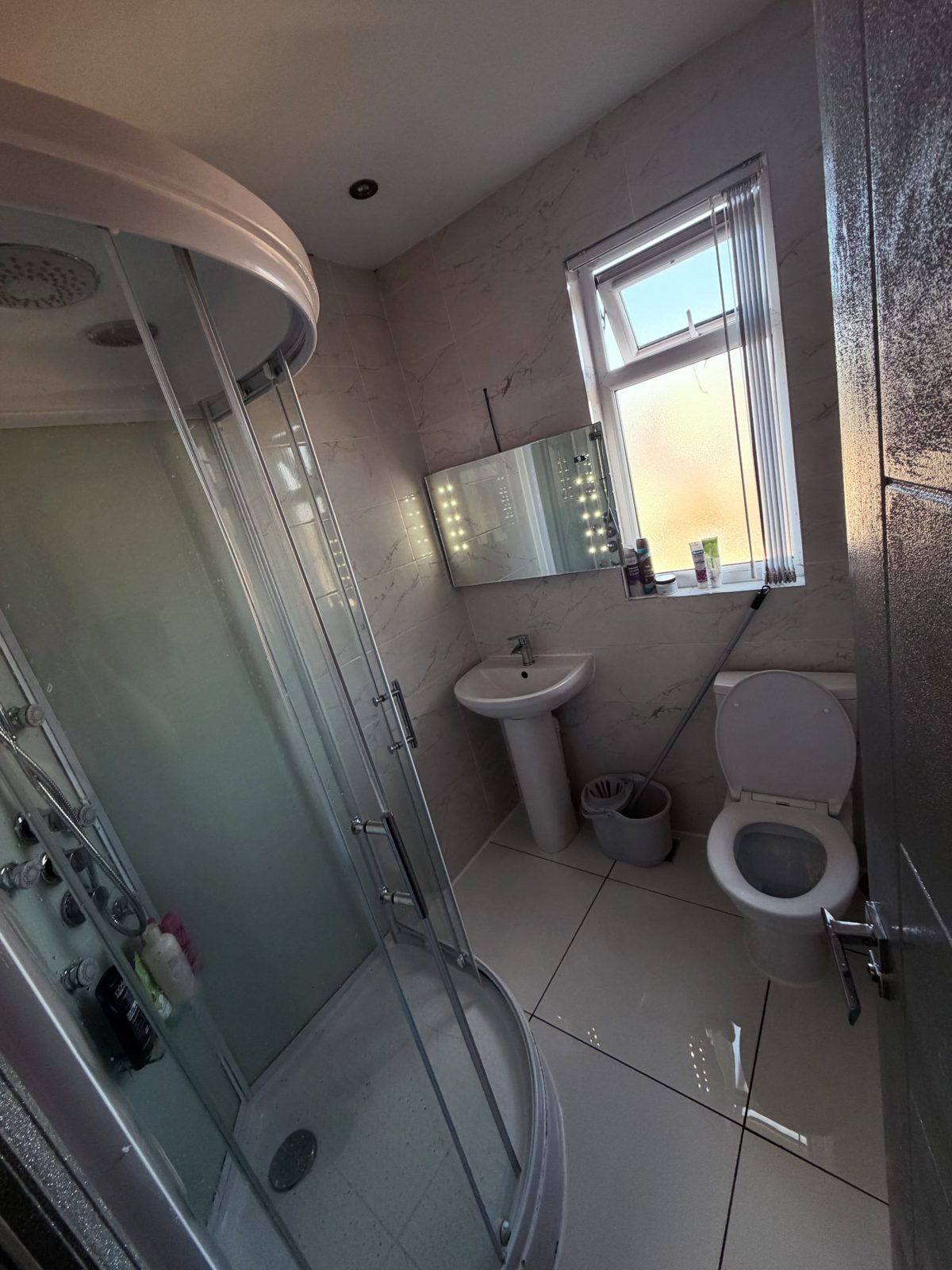 A clean communal bathroom with a corner shower cabin